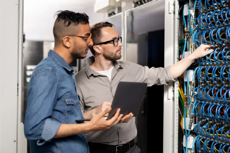 Dos ingenieros con una tablet frente a un rack de red.