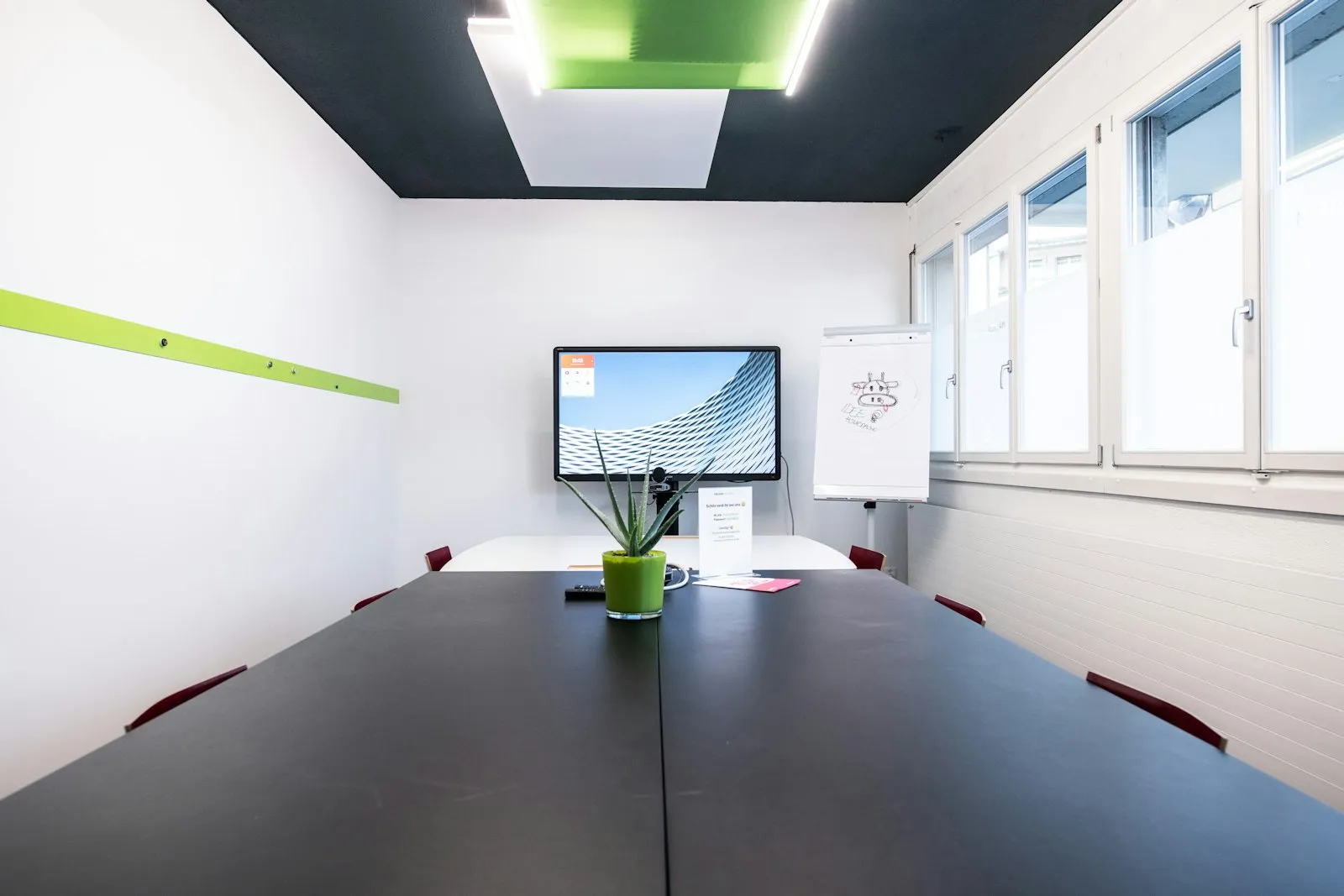 Sala de reuniones con mesa larga y una pantalla en la pared.